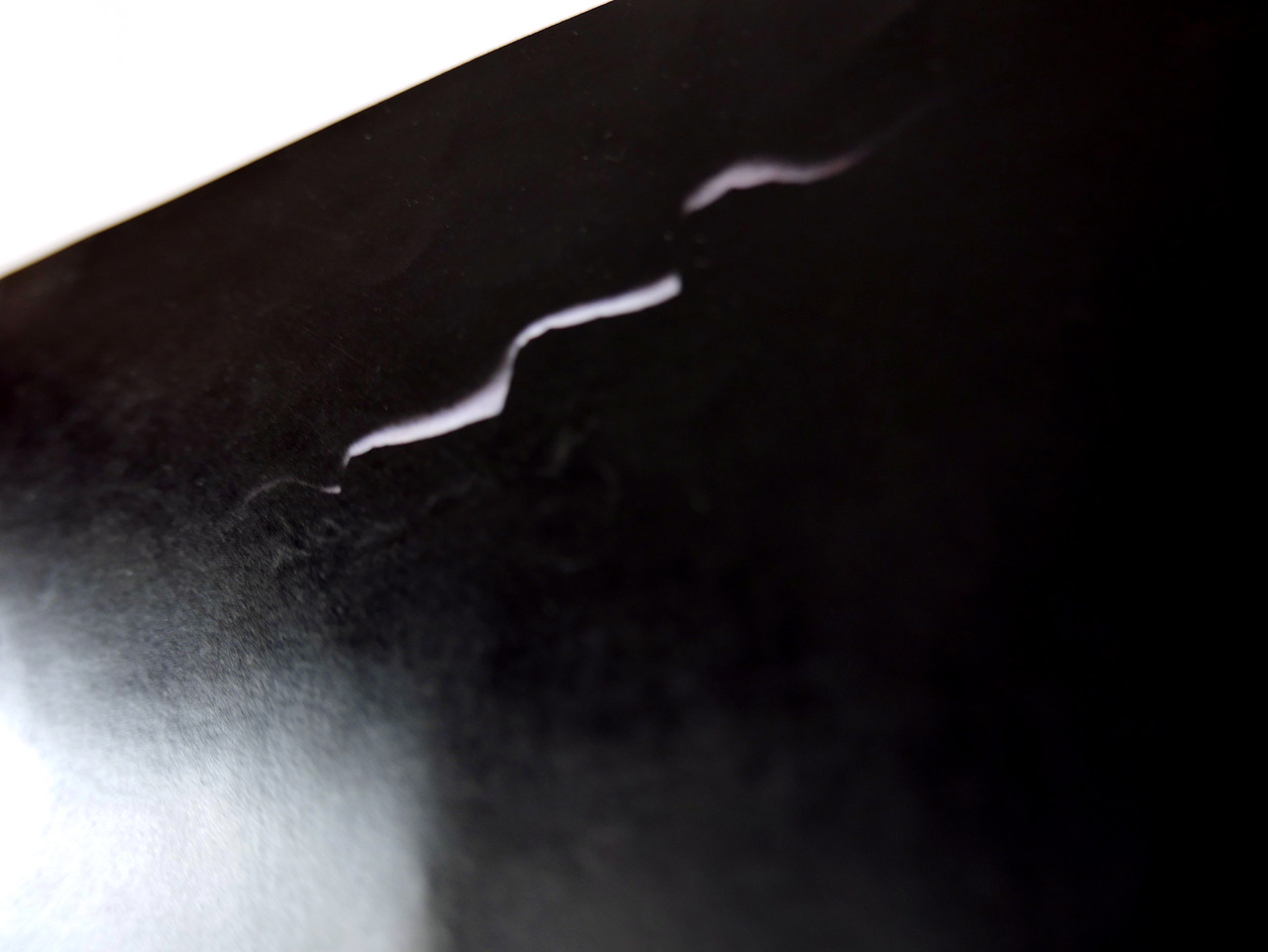 nearly all black photo with a wavy shape of light